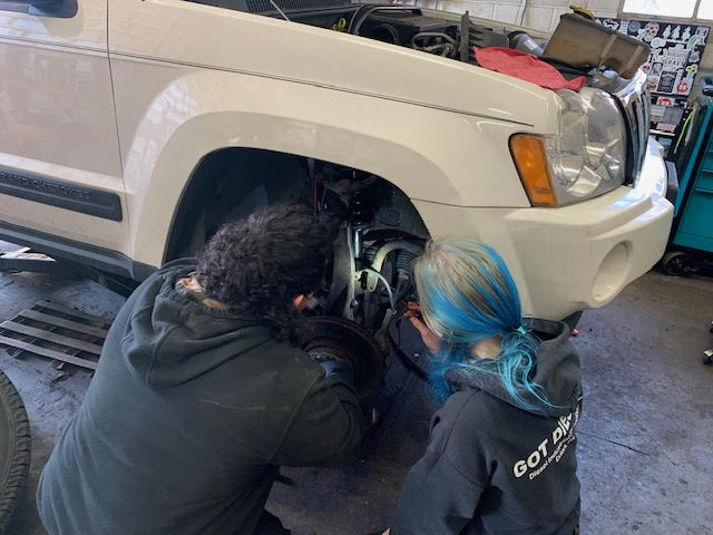 Sebastian Sanchez and Lauren Davidson repairing a car